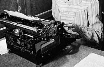 A vintage photograph of someone typing at a typewriter
